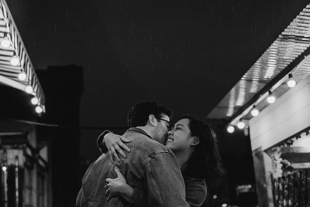 Black and white image of couple in the rain in Brooklyn at night. 